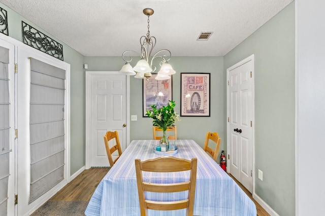 dining space with dark hardwood / wood-style flooring, a chandelier, and a textured ceiling