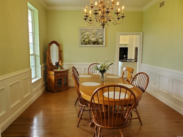 dining space with crown molding, hardwood / wood-style flooring, and a notable chandelier