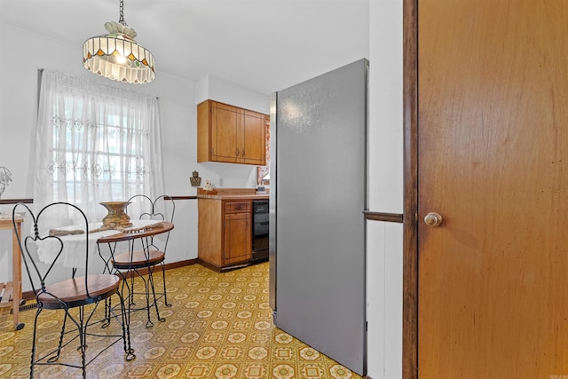 kitchen featuring light tile patterned flooring, dishwasher, hanging light fixtures, and stainless steel refrigerator