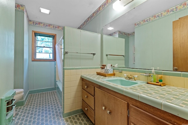 full bathroom featuring tile patterned flooring, toilet, vanity, tile walls, and shower / tub combo