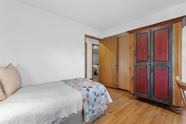 bedroom with light hardwood / wood-style floors and a closet