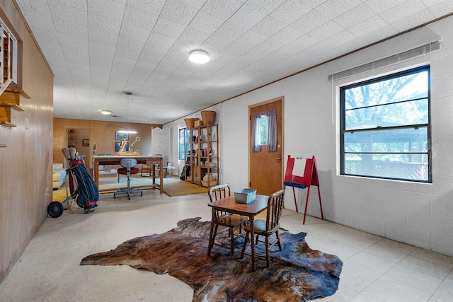 dining room with light tile patterned floors and wooden walls