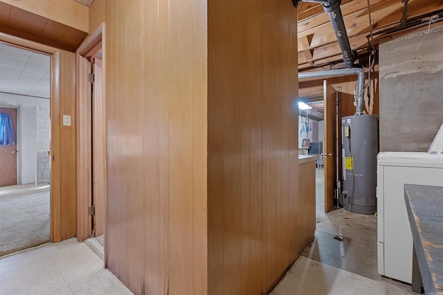 interior space featuring water heater, washer / dryer, and wood walls