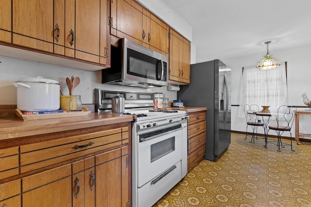 kitchen featuring tile patterned flooring, hanging light fixtures, and appliances with stainless steel finishes