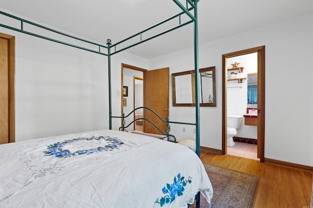 bedroom with connected bathroom and hardwood / wood-style floors