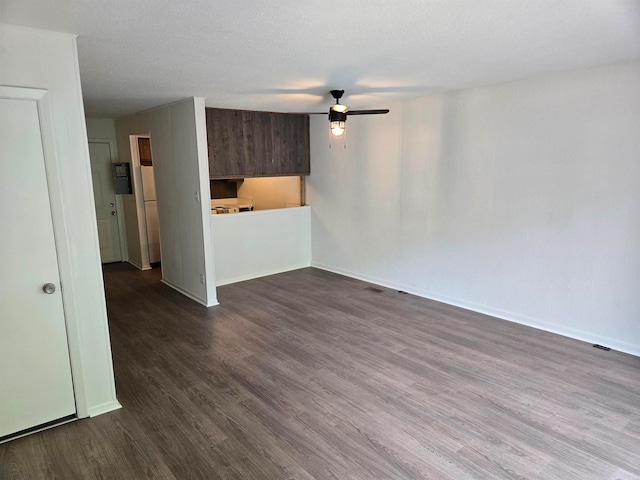 unfurnished living room featuring dark wood-type flooring and ceiling fan