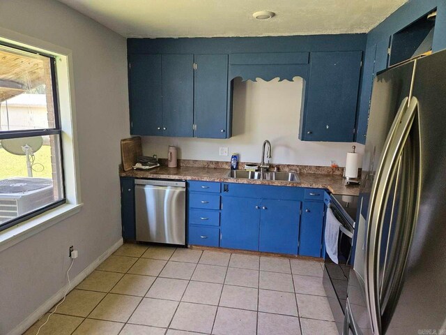 kitchen featuring light tile patterned flooring, blue cabinetry, appliances with stainless steel finishes, and sink