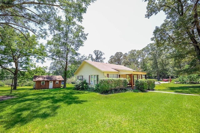 view of front of property with a storage shed and a front lawn