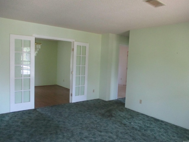 spare room featuring dark colored carpet and french doors