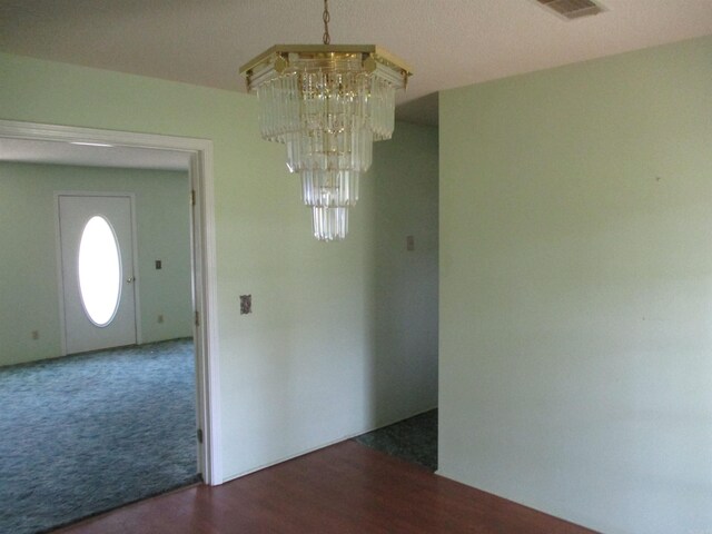 unfurnished dining area with a chandelier and dark carpet