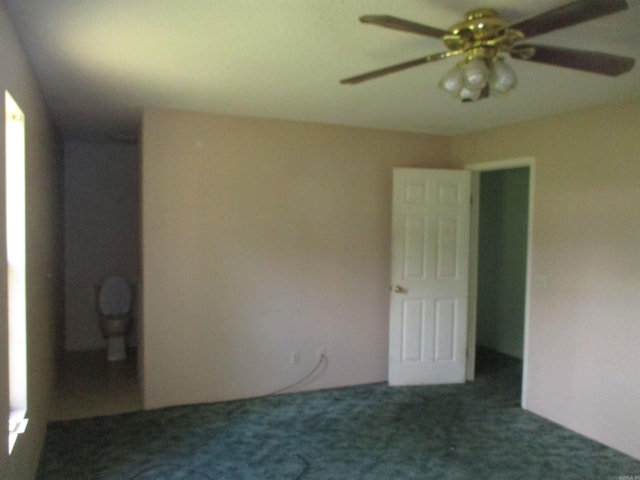 spare room with dark colored carpet and ceiling fan