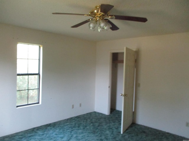 unfurnished bedroom featuring multiple windows, a closet, ceiling fan, and dark carpet