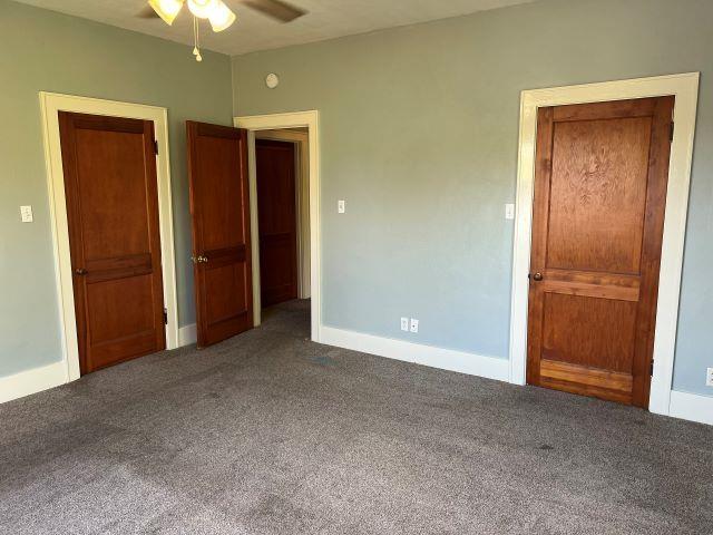 unfurnished bedroom featuring dark carpet and ceiling fan