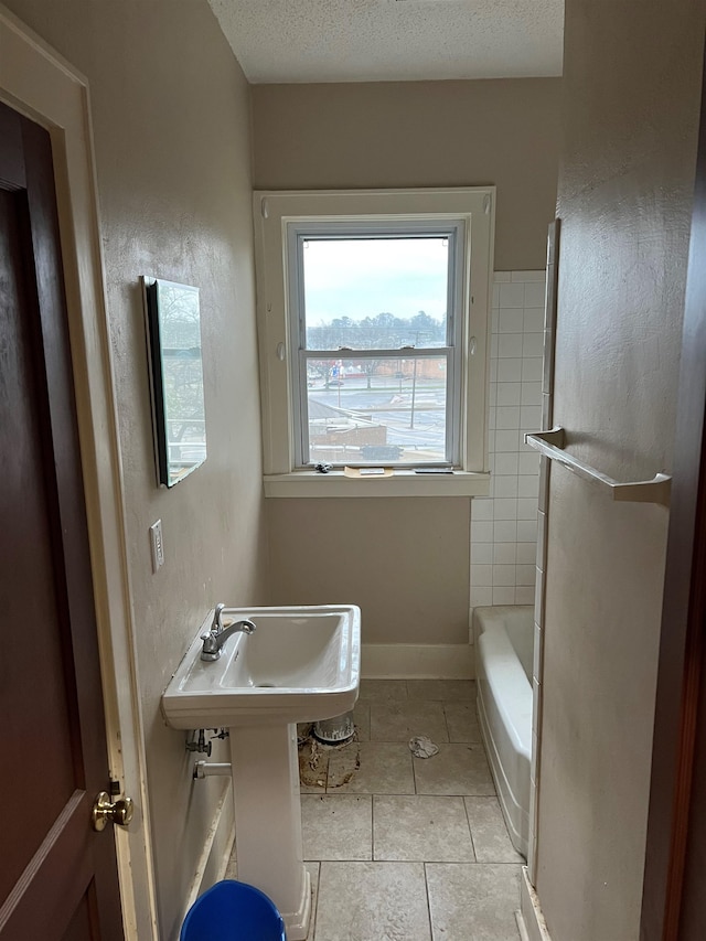 bathroom featuring tiled shower / bath, tile patterned floors, and a textured ceiling