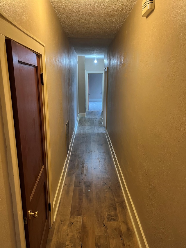 corridor with dark hardwood / wood-style floors and a textured ceiling