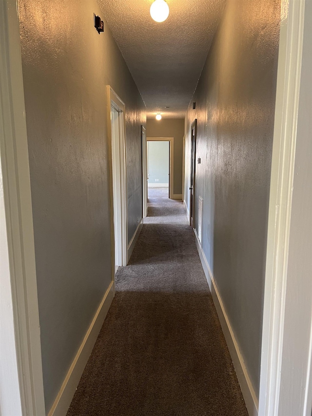 corridor featuring carpet flooring and a textured ceiling