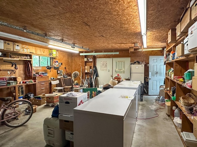 garage with a workshop area, wood walls, and white refrigerator