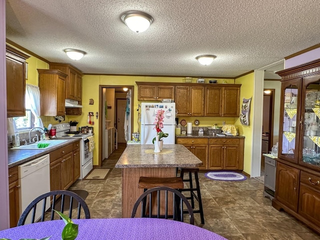 kitchen with ornamental molding, a textured ceiling, white appliances, sink, and a center island