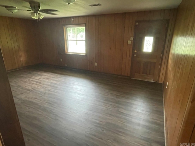 spare room featuring ceiling fan, wood walls, and dark hardwood / wood-style flooring