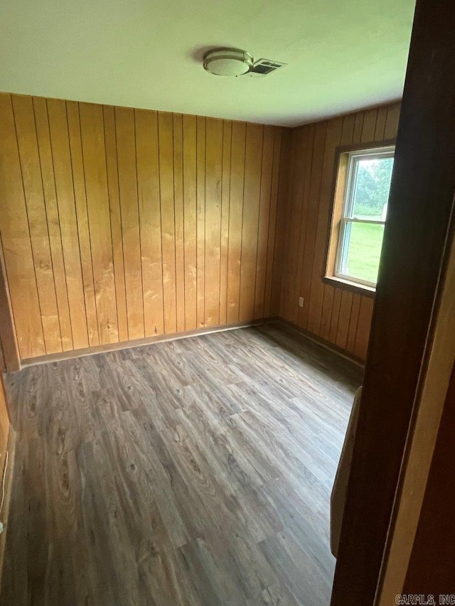 unfurnished room featuring wood walls and hardwood / wood-style floors