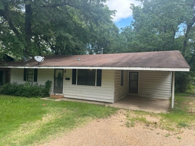 ranch-style house featuring driveway, an attached carport, and a front yard