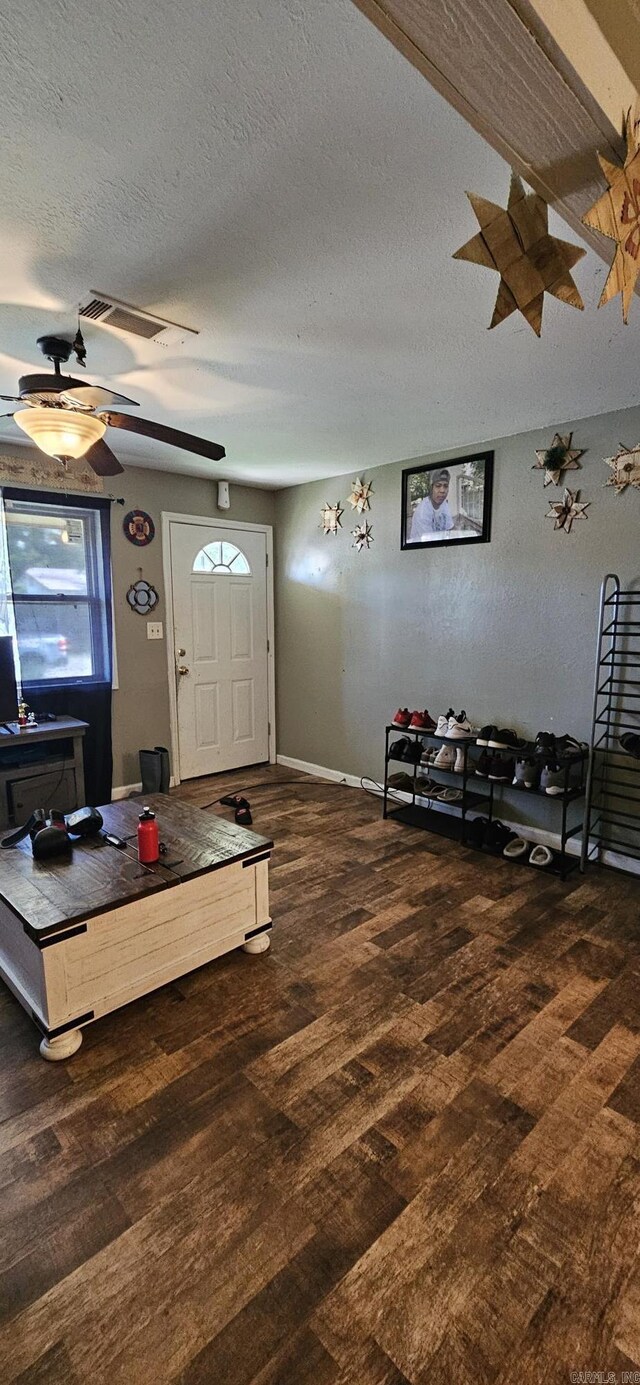 living room featuring dark wood-type flooring, a textured ceiling, ceiling fan, and beam ceiling