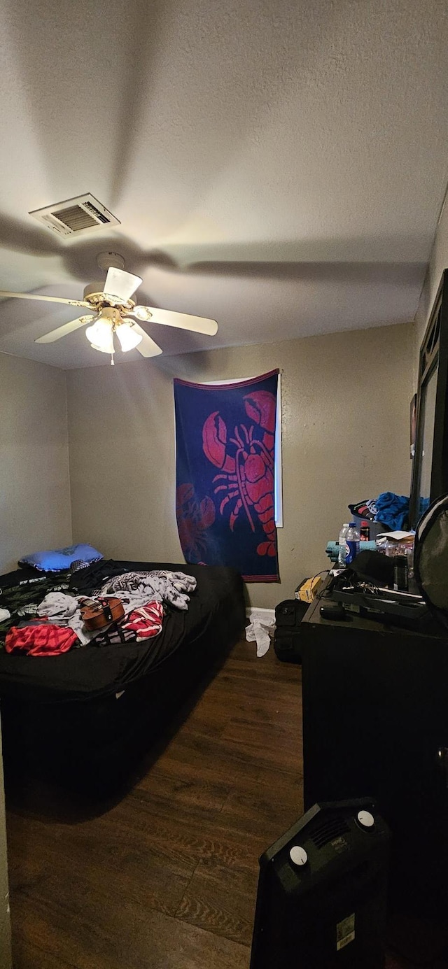 bedroom with dark wood-type flooring, ceiling fan, and a textured ceiling