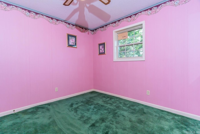 empty room featuring ceiling fan, dark carpet, and a textured ceiling