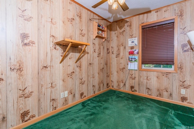 spare room featuring ceiling fan, carpet, wood walls, and ornamental molding