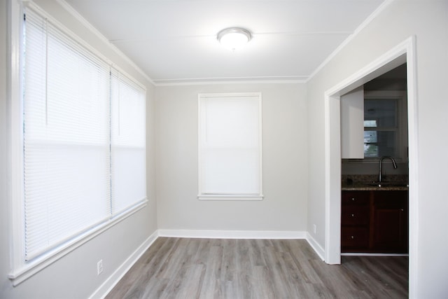 spare room featuring sink, ornamental molding, and light hardwood / wood-style floors