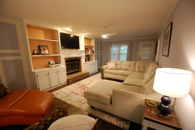 living room featuring crown molding, wood-type flooring, built in features, ceiling fan, and a fireplace