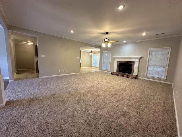 unfurnished living room featuring a brick fireplace, crown molding, light colored carpet, and ceiling fan