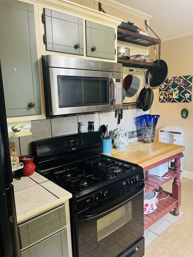 kitchen with black range with gas stovetop, decorative backsplash, tile counters, and crown molding