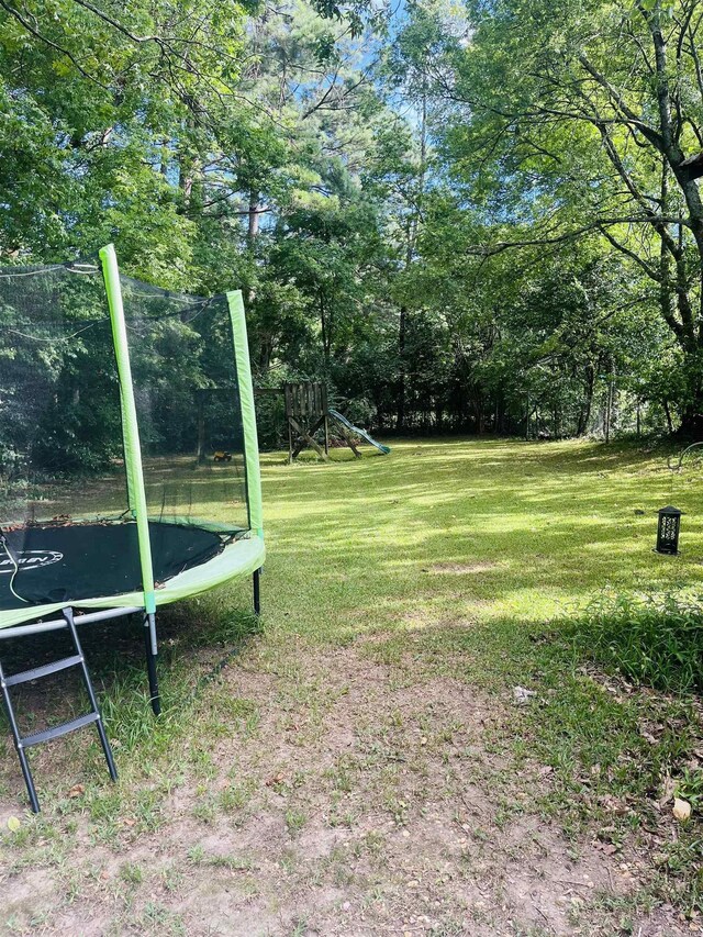 view of yard featuring a trampoline and a playground