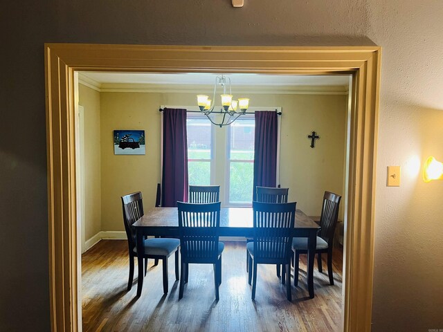 dining area with hardwood / wood-style floors, a chandelier, and ornamental molding