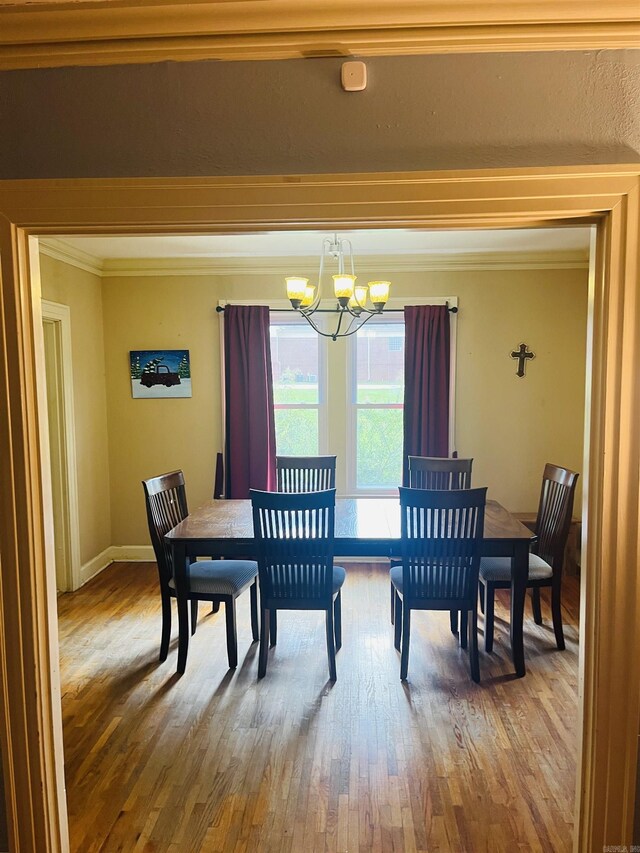 dining space featuring wood-type flooring, a notable chandelier, and ornamental molding