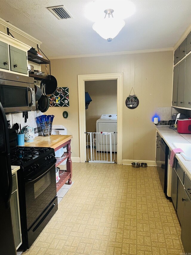 kitchen with ornamental molding, black appliances, and washer / dryer