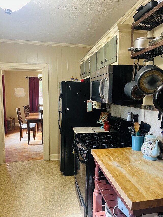 kitchen with light hardwood / wood-style floors, green cabinetry, crown molding, and black gas range