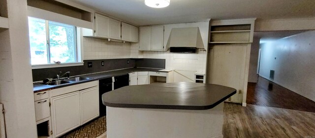 kitchen with sink, custom range hood, white cabinets, and a kitchen island