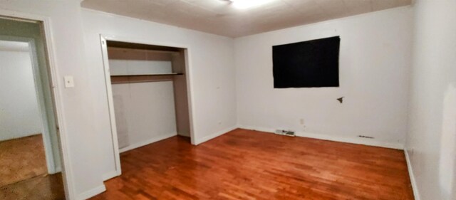 unfurnished bedroom with hardwood / wood-style flooring and a closet