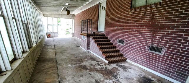 interior space with vaulted ceiling, concrete flooring, and brick wall