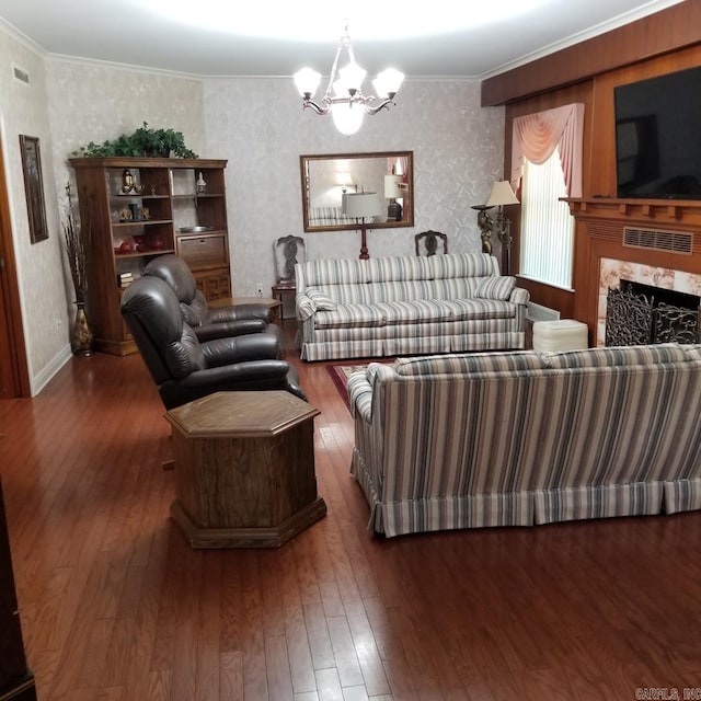 living room featuring dark hardwood / wood-style floors, a premium fireplace, crown molding, and an inviting chandelier