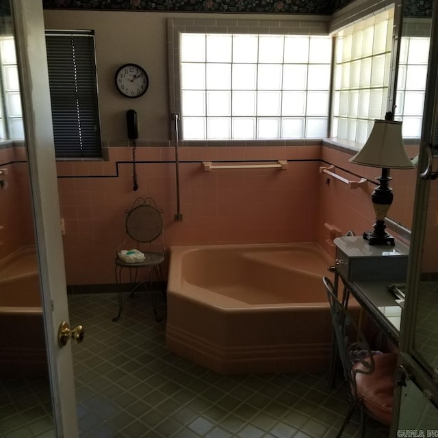 bathroom with tile patterned flooring, a tub to relax in, and tile walls