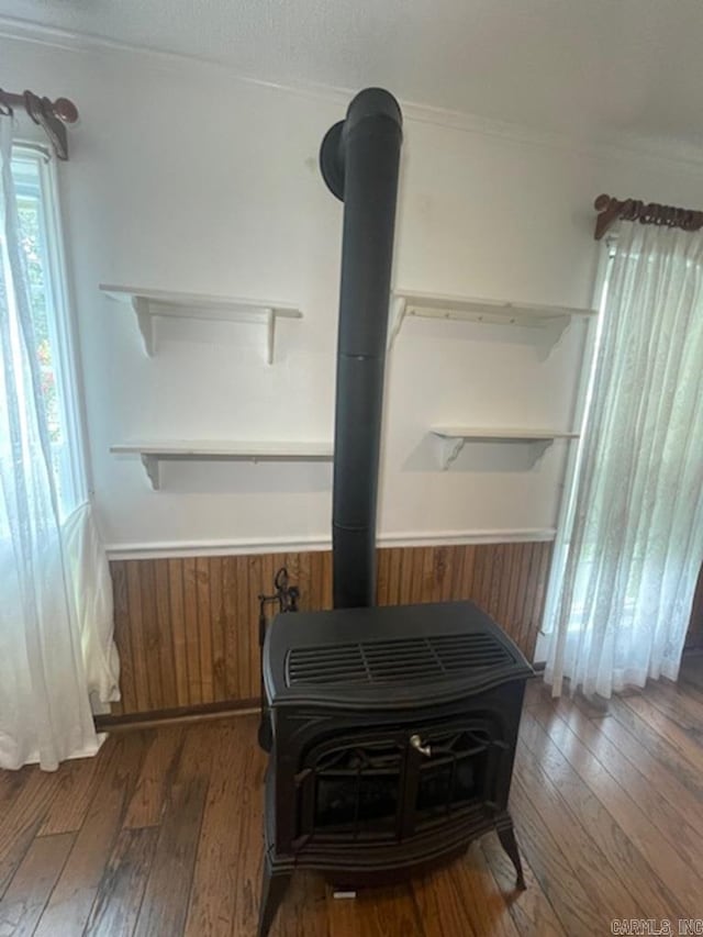 room details with wood-type flooring, a wood stove, and ornamental molding