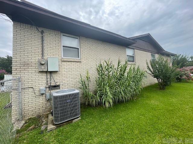 view of home's exterior with cooling unit and a lawn