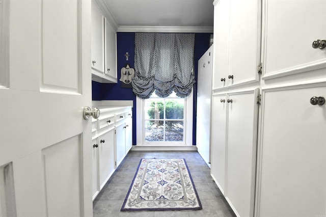 kitchen with white refrigerator, crown molding, and white cabinets