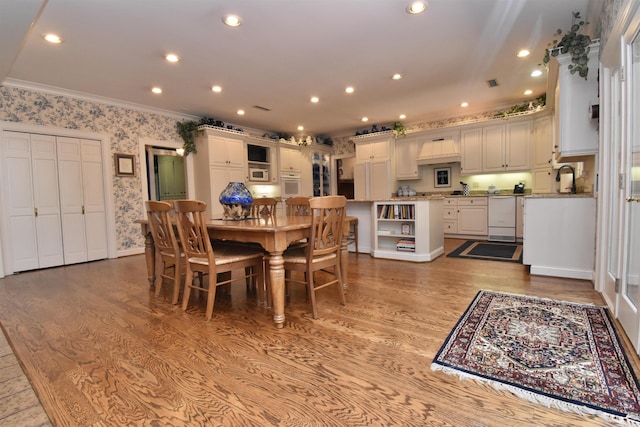 dining room with crown molding, sink, and light hardwood / wood-style floors