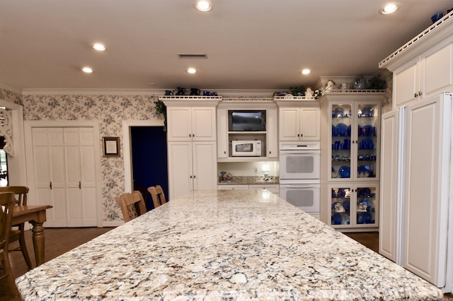 kitchen featuring white cabinetry, white appliances, and light stone countertops