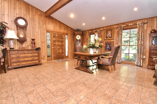 dining space featuring lofted ceiling with beams and wood walls