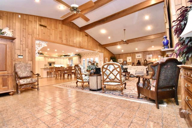 living room featuring beamed ceiling, high vaulted ceiling, ceiling fan, and wood walls